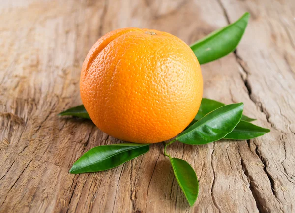 Fruit orange avec feuilles sur fond en bois — Photo