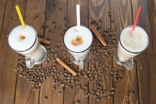 Latte con semillas de café sobre fondo de madera — Foto de Stock
