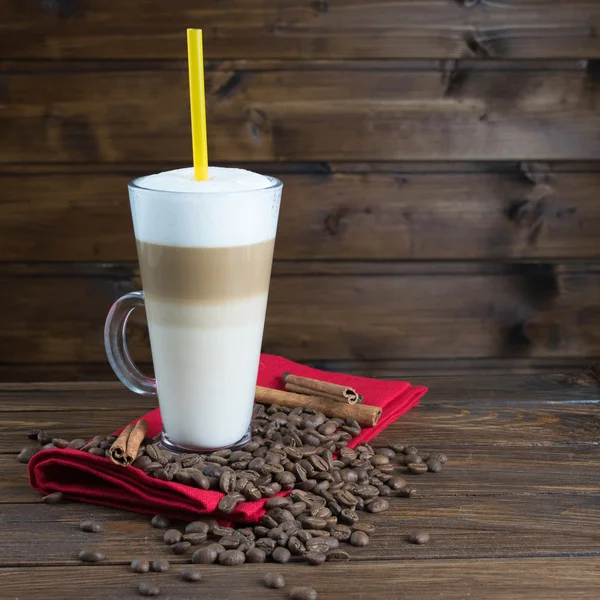 Latte com sementes de café em fundo de madeira — Fotografia de Stock