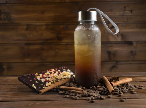 Café gelado em garrafa e chocolate em um fundo de madeira — Fotografia de Stock