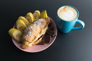 Kruvasan çikolata, pembe plaka ve c mavi bardak muz ile