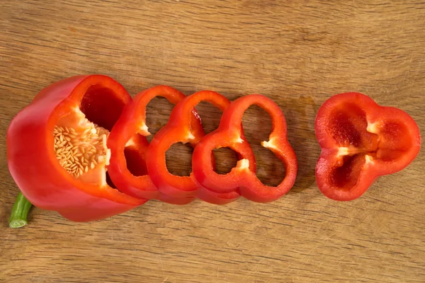Sliced red sweet pepper isolated on wooden background