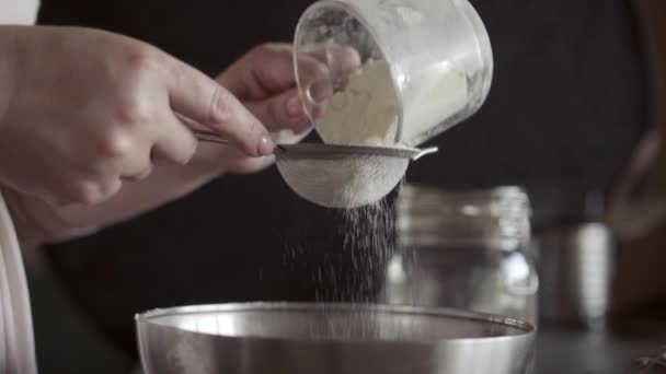 Przesiewanie mąki przez małe sito metaliczne, zbliżenie, makro, kobiece dłonie — Wideo stockowe