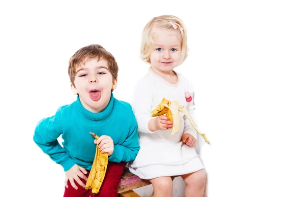 Niño y niña comiendo bananos — Foto de Stock