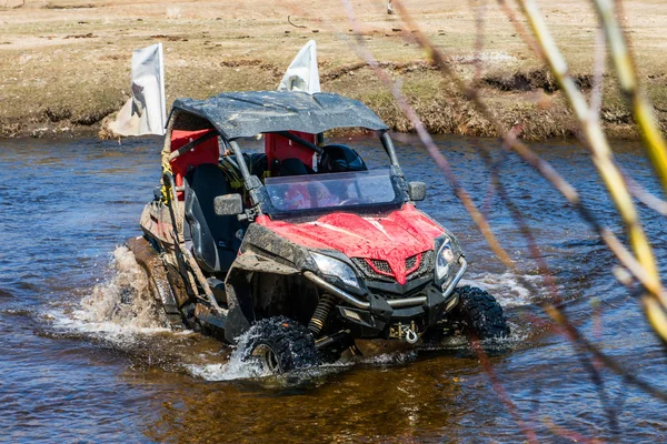 The man on the ATV rides on the river with a splashing water — Stock Photo, Image