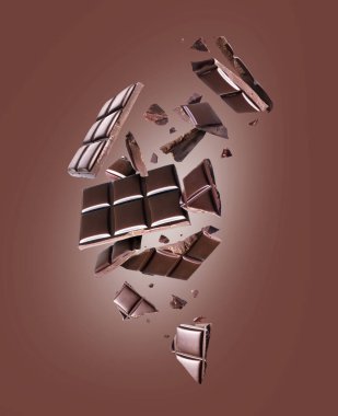 Kahverengi bir arka planda havada ezilmiş siyah çikolata çubuğu.