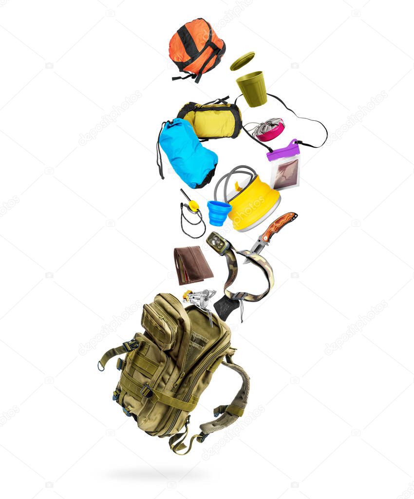 Various travel accessories flying out from military backpack, isolated on white background