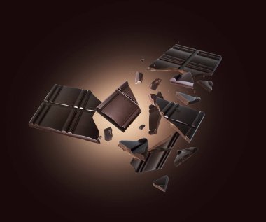 Kahverengi arka planda havada uçuşan parçalarla parçalanmış siyah çikolata.