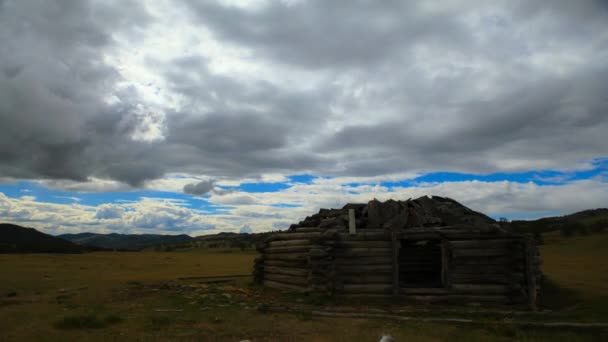 Белые облака на голубом небе над маленьким деревянным домом . — стоковое видео