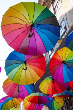 Renkli Gökkuşağı Şemsiyeleri Mavi Bina Arkaplanına Karşı İplerde Asılı. Sokak tesisi. Şehir sanatı. Yaz festivali dekorasyonu. Canlı renkler.