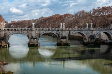 Roma 'daki Tiber Nehri' ni sakin su yansımalarıyla geçen tarihi taş köprü. Klasik Avrupa şehir simgesi mimari, tarih ve seyahat cazibesini birleştiriyor.
