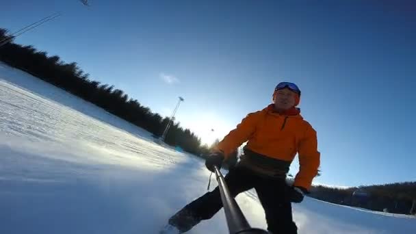 Hombre montando en esquí con palo de selfie en la mano — Vídeo de stock