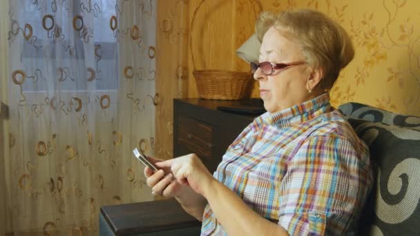 Старуха использует смартфон дома — стоковое видео