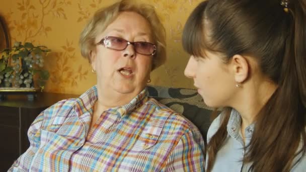 Mulher velha e jovem olhando para o álbum de fotos da família no sofá em casa — Vídeo de Stock