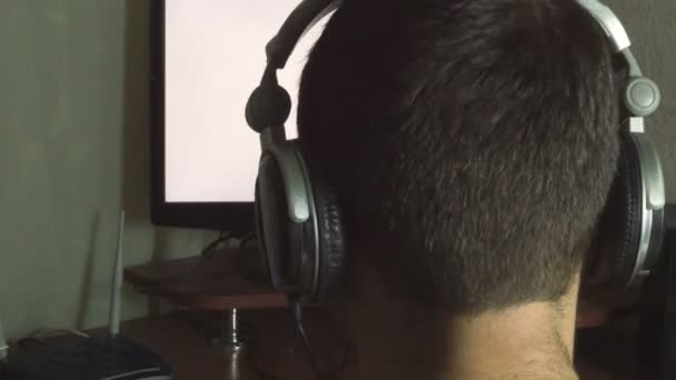 Man listening to music at night in a dark room back view — Stock Video