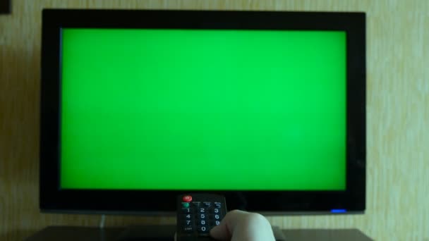 Male hand with TV remote switching channels on green screen TV point of view — Stock Video