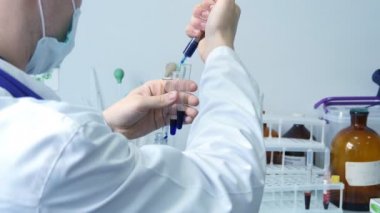 Arkadan görünüş bir kimyasal testi tüpler içine enjekte ve üç test tüpleri mavi madde ile tutarak erkek bilim adamı doktor