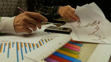 Genç işadamı ve grafikleri analiz, hesaplamalar yapmak ve not alma işkadını