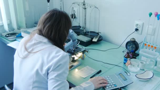 Női orvos tudós lab kutató látszó átmenő a Mikroszkóp. Vértes szemcsésedik-ból folyamat orvosi vizsgálat — Stock videók