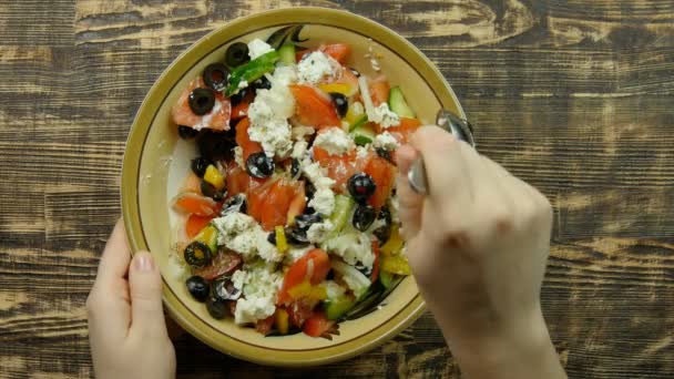 Female hand stirring fresh vegetable salad with cheese feta in the kitchen . The mixing of vegetables. Close-up — Stock Video
