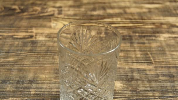 Du lait naturel frais est versé d'un bol dans le gobelet en verre transparent sur la table en bois. Alimentation saine, concept de régime alimentaire et boissons, macro gros plan — Video