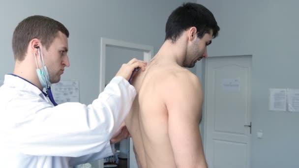 Arzt untersucht Rücken junger männlicher Patientin mit Stethoskop