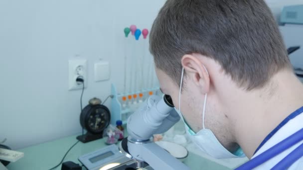 Νέος επιστήμονας, εργάζονται με ένα μικροσκόπιο σε εργαστήριο — Αρχείο Βίντεο
