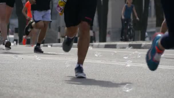 La gente bebe el agua y arroja vasos de plástico a la calle. Maratón de la ciudad. Pies de personas . — Vídeo de stock