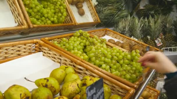 Hembra mano la elección de las uvas en la tienda — Vídeo de stock