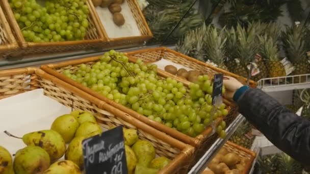 Привлекательная девушка выбирает виноград в магазине — стоковое видео