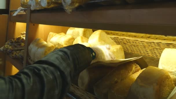 Женщина выбирает и кладет свежий хлеб в бумажный пакет в супермаркете — стоковое видео