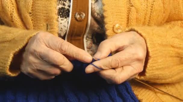 Die alte Frau sitzt zu Hause und strickt Kleidungsstücke — Stockvideo