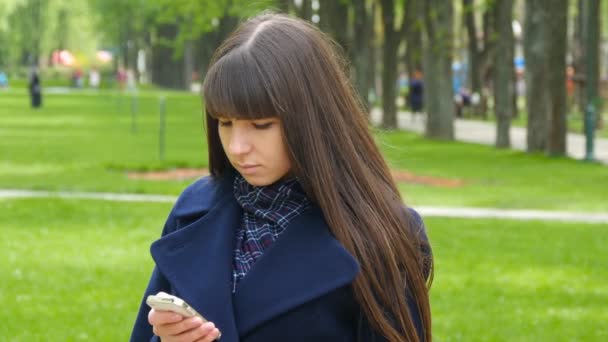 Bella donna utilizza smartphone cellulare all'aperto nel parco dettaglio. Giovane ragazza felice attraente si rilassa in un parco cittadino — Video Stock