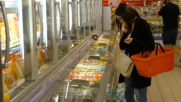 Молода жінка купує молочні або холодильні продукти в супермаркеті — стокове відео