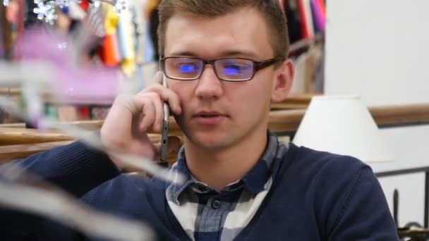Uomo in occhiali che parla al telefono al centro commerciale e lavora con il computer portatile — Video Stock