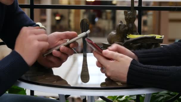 Mani di coppia che utilizzano gli smartphone insieme al caffè nel centro commerciale. Primo piano di uomo e donna informazioni di navigazione e scorrimento immagini su smart phone — Video Stock