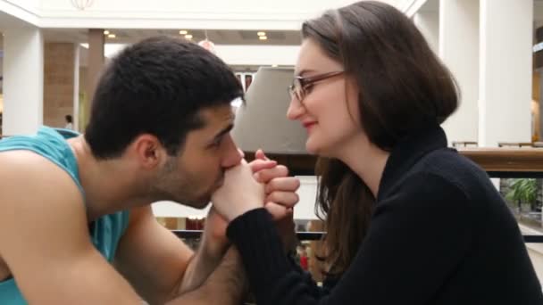 Happy couple holding and touching each others hands at cafe in shopping mall and kissing — Stock Video