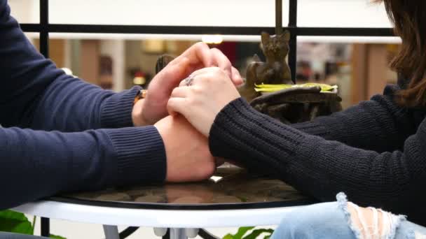 Happy couple holding and touching each others hands at cafe in shopping mall. — Stock Video