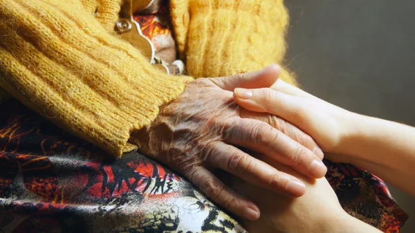Старушка молодая девушка держит руку морщинистая кожа близко — стоковое фото