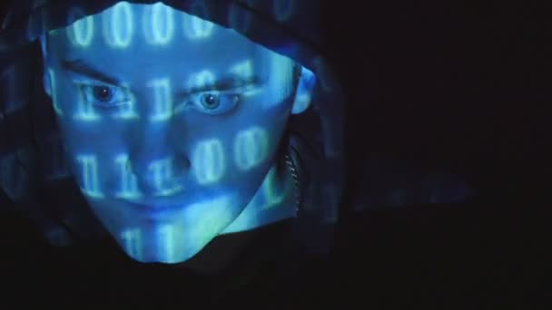 バイナリ コード予測を持つハッカーの男性の顔のショットを閉じる。怒っている敵に投影されるソース コード マンの顔、黒背景. — ストック動画