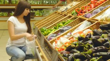 Genç güzel kız biber bir bakkal süpermarket seçmektir. Çekici kadın markette taze yeşil biber seçme üretmek bölümü.