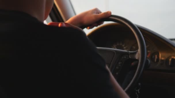 Young man driving a car. Serious guy drive car along country road, view from inside car. Rear back view, steadicam shot, close-up — Stock Video