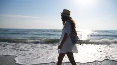 Okyanus kıyısında yürüyen, plaj kıyafetli genç bir bayan yürüyüşçü. Sırt çantalı çekici bir kadın sahilde geziniyor ve güzel manzaraya hayran. Deniz manzaralı deniz kıyısına giden bir kız. Yavaş çekim