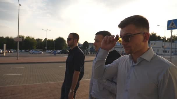 Three young businessmen walking in city with sun flare at background. Business men commuting to work together. Confident guys being on his way to office. Colleagues going outdoor. Slow motion Close up — Stock Video