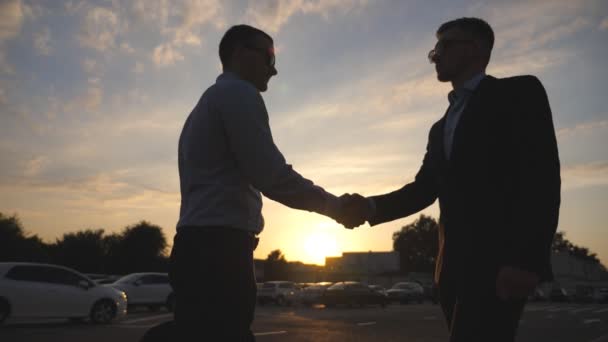 Twee jonge zakenmannen nemen afscheid en knuffelen elkaar buiten. Collega 's of zakenpartners omarmen en verschillen met de zon op de achtergrond. Uit elkaar gaan tussen goede vrienden buiten. Langzame beweging — Stockvideo