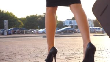 Havaalanından ya da bekleme odasından bavuluyla yürüyen bir iş kadını. Terminalden çıkıp tekerlekli bavula binen topuklu genç bir kız. İş kadını caddeye çıkıyor. Yavaş çekim