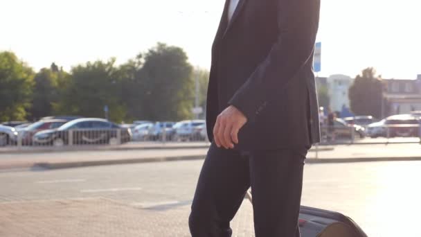 Crane shot of young businessman walking on city street with his luggage after flight. Successful male business person going on urban environment and pulling suitcase on wheels. Slow motion Side view — Stock Video