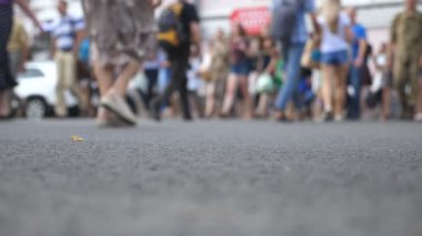 Büyük şehirde yaz günü, tanınmayan yayaların kavşaktan karşıya geçerken alçak açılı görüntüsü. Şehir merkezinde yaya geçidinde yürüyen bir kalabalık. Kentsel yaşam tarzı kavramı. Bulanık hareket. Yavaş çekim