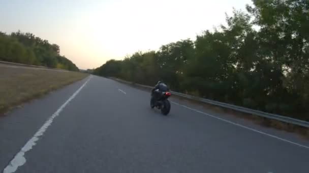 Байкер прискорюється на мотоциклі на порожній заміській дорозі. Чоловік швидко їде на сучасному спортивному мотоциклі на осінньому шосе. Хлопець їде на велосипеді під час подорожі. Концепція свободи та пригод. Повітряний постріл — стокове відео