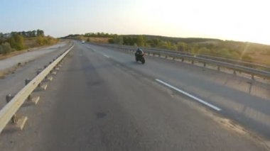 Güneşli bir sonbahar gününde otoyolda motosiklet süren motosikletliyi takip edin. Motosikletli, kır yolunda motosikletiyle yarışıyor. Yolculuk sırasında bisiklet süren bir adam. Yolculuk kavramı. Hava görüntüsü